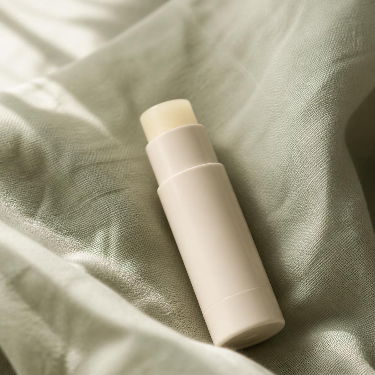 GentleBalm lip balm lying on softly folded sage-green linen
